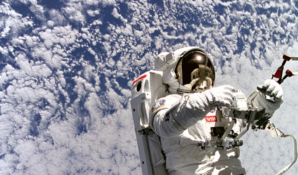 Backdropped against clouds 130 nautical miles below, astronaut Mark C. Lee floats freely without tethers as he tests the new Simplified Aid for EVA Rescue (SAFER) system. Image courtesy of NASA