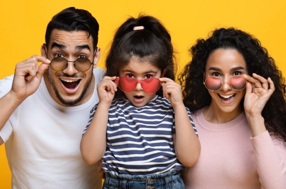 A family looks surprised as they try on colored sunglasses.