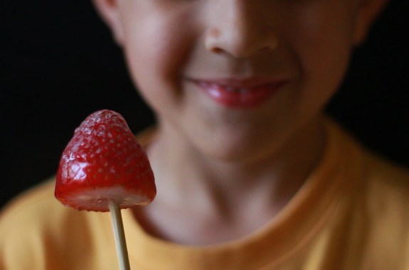 boy holding a strawberry on a stick