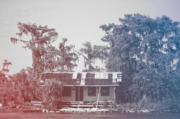 red and blue tinted image of abandoned house in the bayou