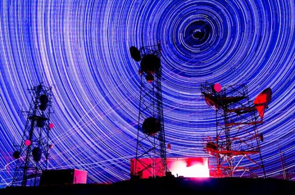time lapse of spinning stars in the background and static, still radio towers in the foreground at night