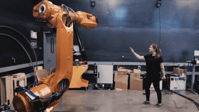 an orange robotic arm responds to the movement of a scientist's gestures