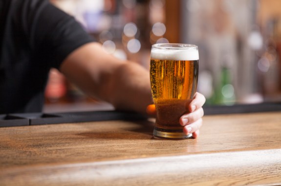 bartender pushing glass of beer across the bar
