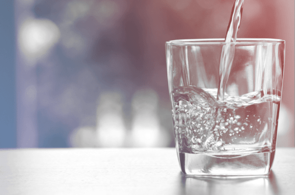 drinking glass on table with water pouring in with red and blue gradient