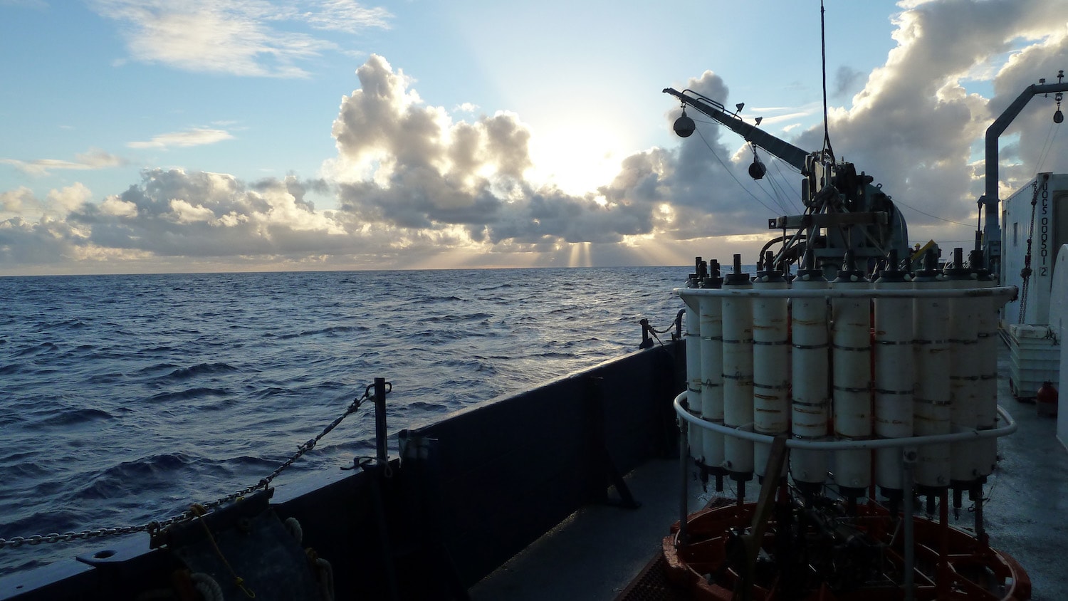 the side of a ship and ocean and sunset in the background