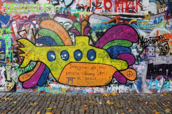 a wall with graffiti and a yellow submarine in the center with beatles lyrics around it
