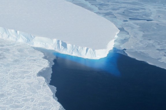 an arial shot of a large chunk of a glacier missing