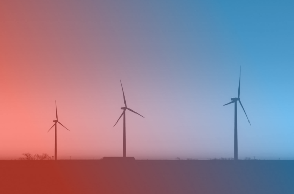 three wind turbines silhouetted against a setting sun