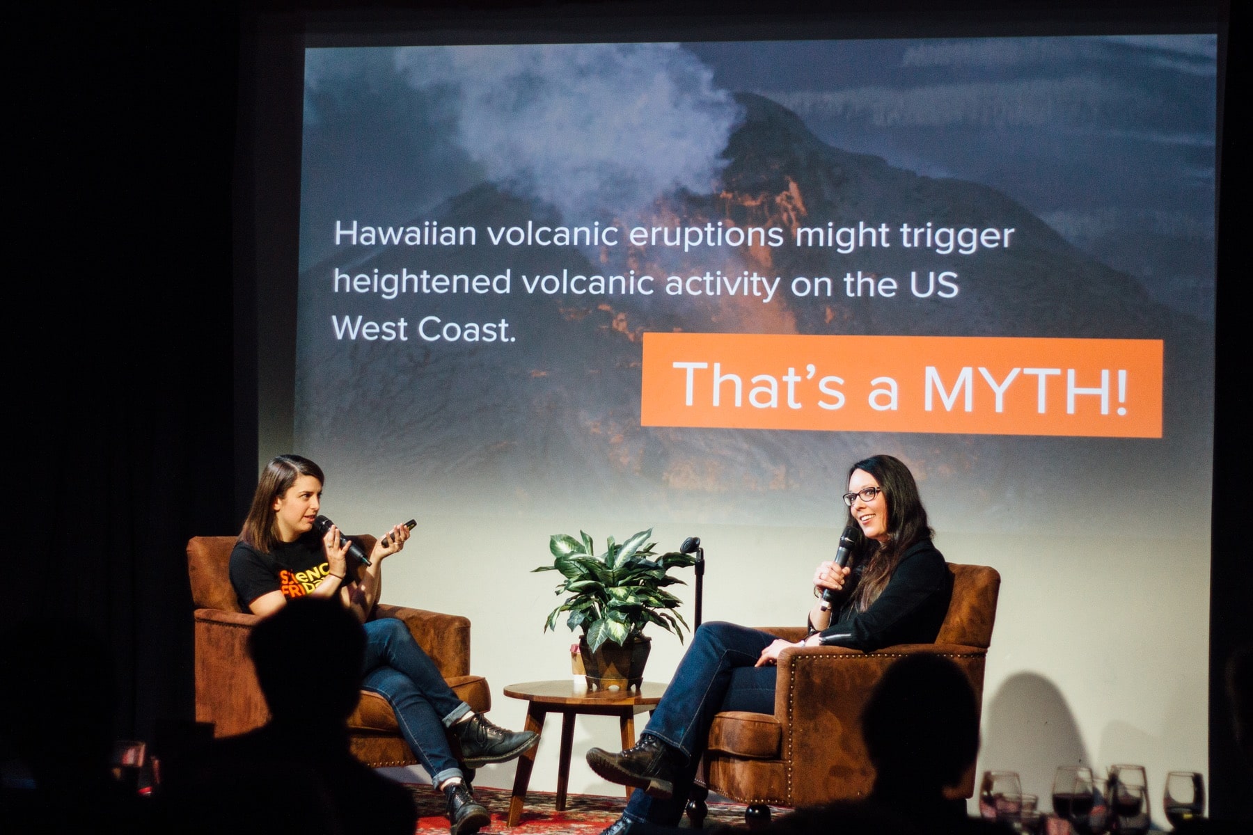 two women sitting onstage with microphones with a plant in between them with a slide in the background that says 'hawaiian volcanic eruptions might tirgger heightened volcanic activity on the US west coast. That's a myth.'