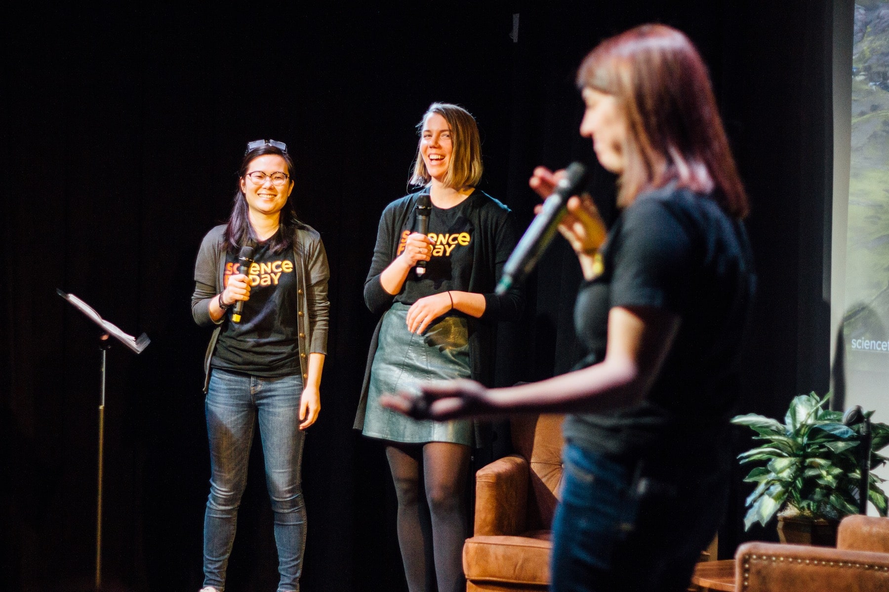 three women on stage, all smiling and laughing