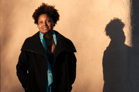 woman in jacket standing in front of wall