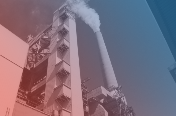 a red and blue filtered image over a power plant, with a giant tall smoke stack