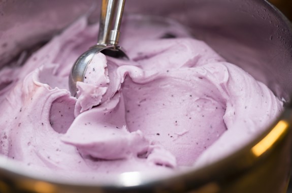 a pink creamy close up of a bowl of ice cream with a scooper