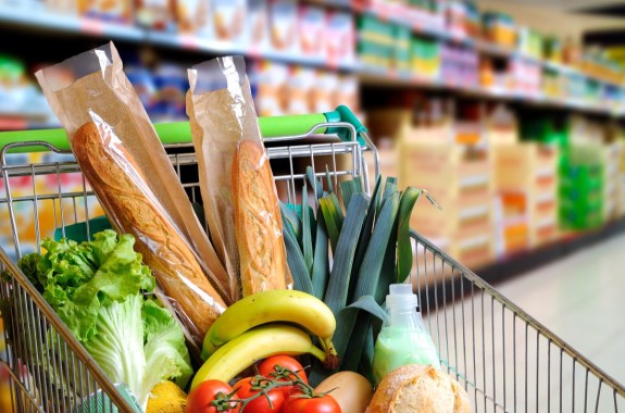 a metal shopping cart overflowing with a variety of produce and bread