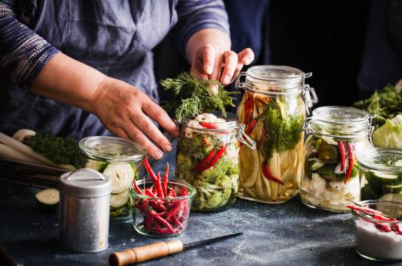 someone bottling jars of pickled foods on a table