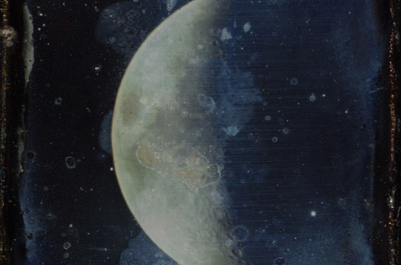 a faded photograph of the moon half obscured in shadow