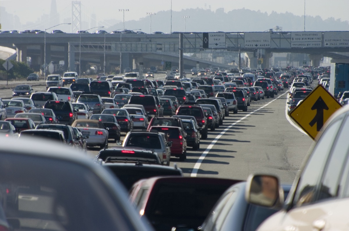 cars wait in traffic on a highway, with smoggy air in the background