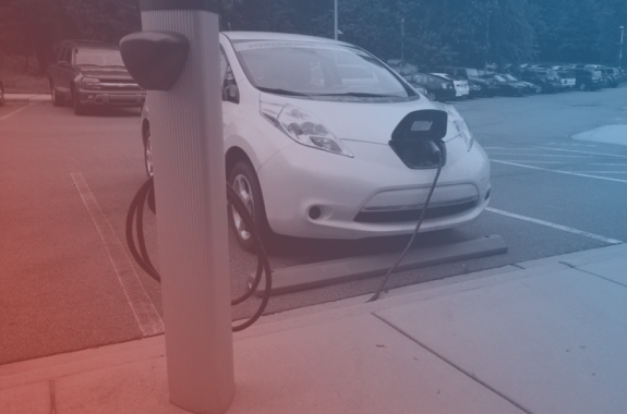a white electric car is charging on a pump. there is a red and blue filter over it