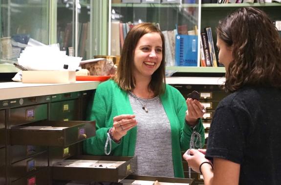 a woman with something in her hand in an office smiling at another woman