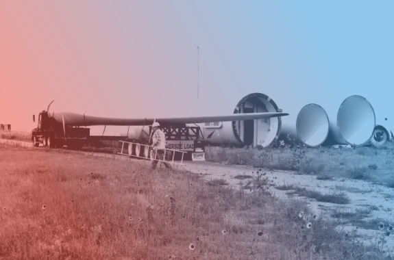 four giant wind turbine blades lay on their side on the ground