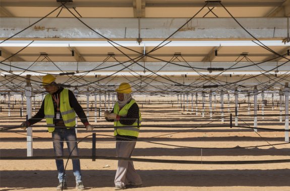 workers install solar panels in the desert
