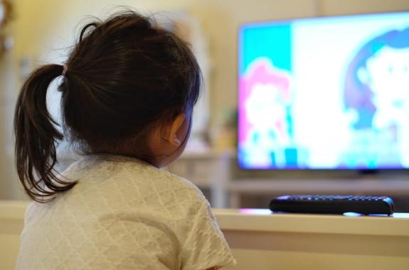 a little girl watches a flat screen television
