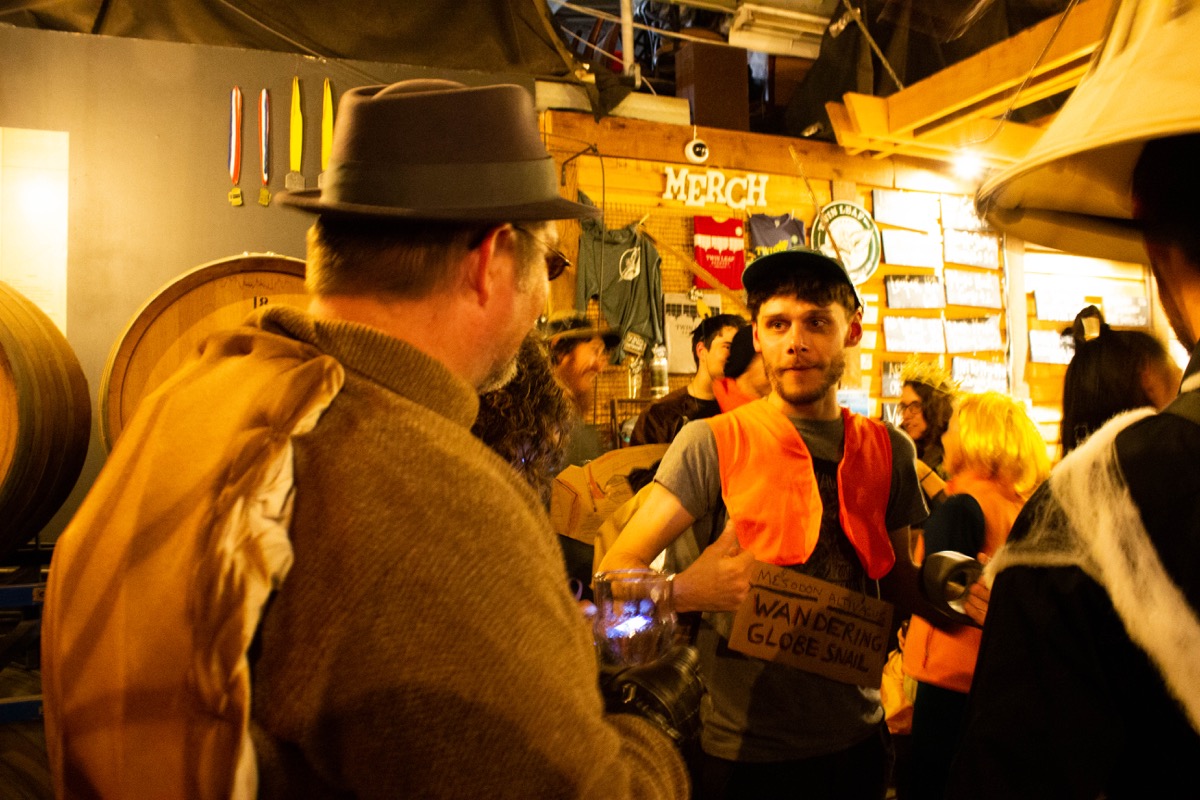two men dressed as a snail and a lichen talk to each other at a bar