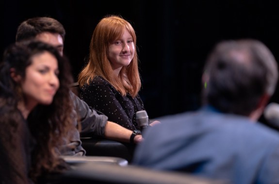 four people on stage with one person in focus holding a mic