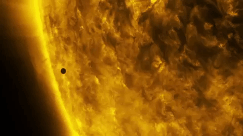 a time lapse from a telescope of a black dot moving in front of the sun