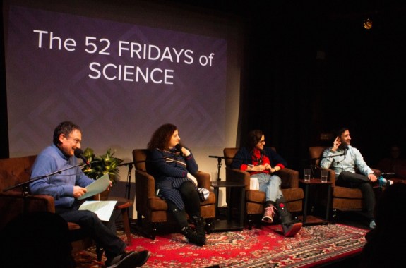 four people on stage in an interview with a slide in the background that reads "the 52 fridays of science"
