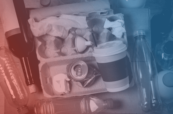 a pile of food waste including cardboard, coffee cups, apples, and soda cans