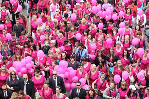 dozens of people in pink t-shirts with pink balloons