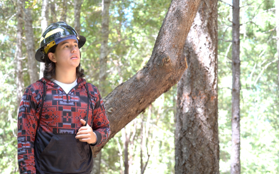 a young man wears a protective helmet as he stands in the forest