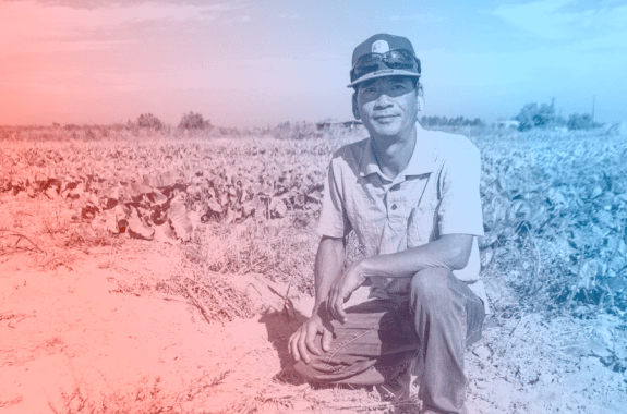 a man kneels in a field of plants