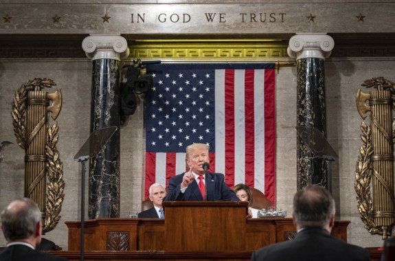 a man stands at a podium in front of the american flag