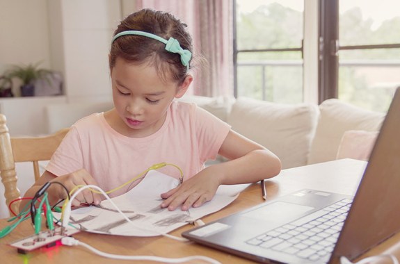 Child working with circuit in front of a laptop