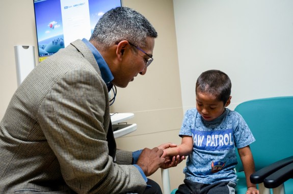 a man looks at a boy's arm that has a red spot on it in a doctor's office