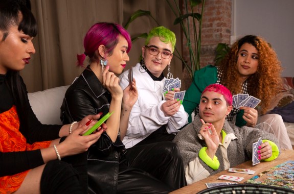 A group of friends of varying genders playing cards from the side