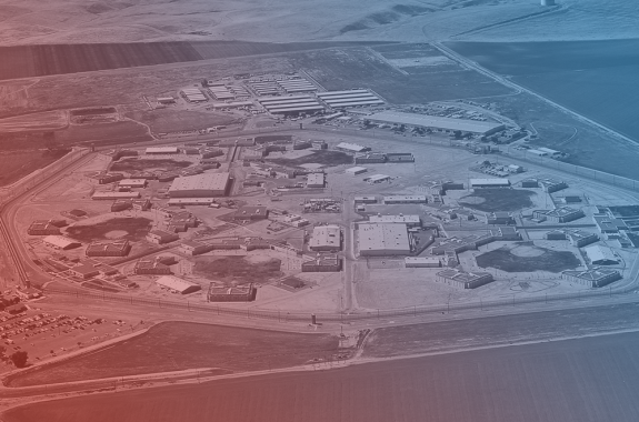 an overhead shot of a bunch of buildings, avenal state prison. the image has a blue and red filter