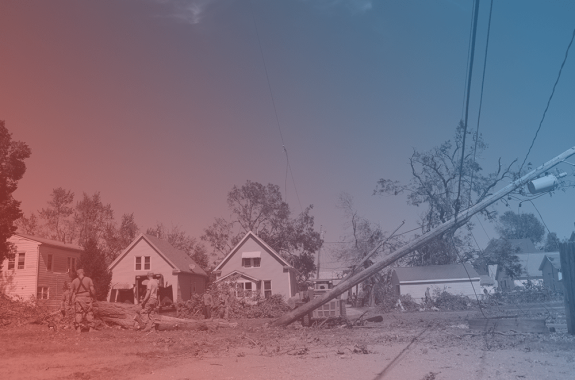 a bunch of downed trees and power lines in front of a row of houses. there is a blue and red filter over the image