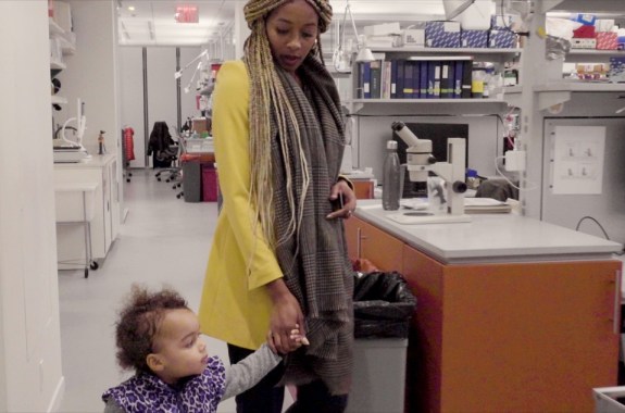 a black women and her child walk hand in hand through the woman's neuroscience lab
