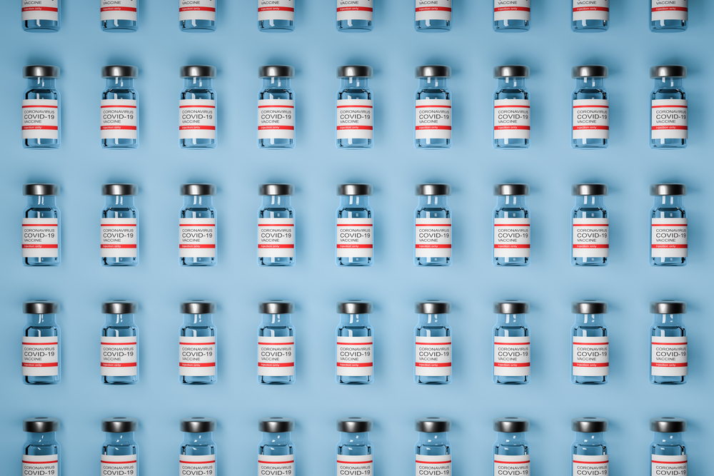pattern of vaccine bottles against covid-19 with injection fluid. Coronavirus vaccine on Blue background