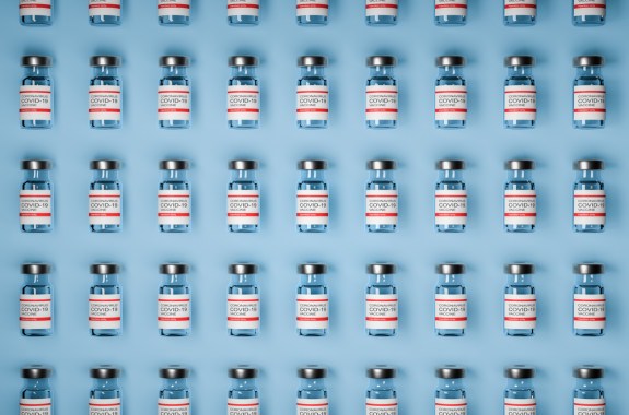 pattern of vaccine bottles against covid-19 with injection fluid. Coronavirus vaccine on Blue background