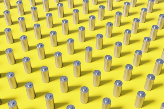 dozens of rows of silver AA batteries on a yellow background