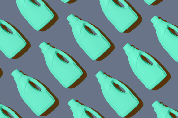 blue colored plastic bottles of cleaning product lined up on a gray background