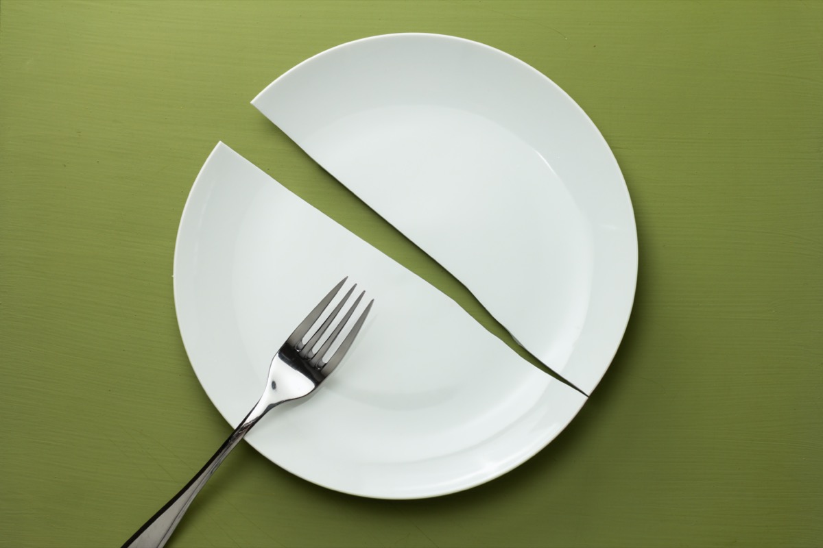 a white plate broken in half with a fork on it on a green background