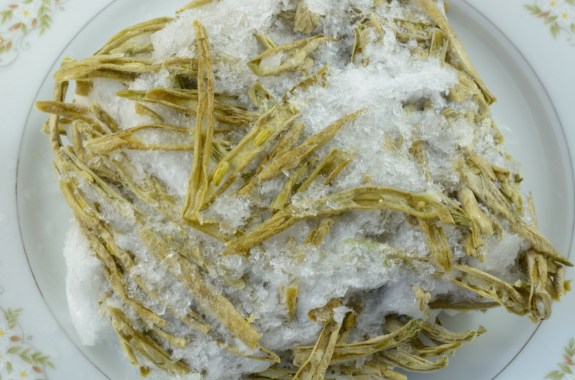 a plate of pale green beans with ice all over it