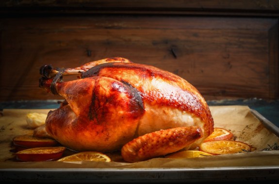 Roast whole turkey over wooden background, side view