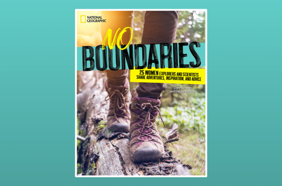 a book cover of a hiker from the knees down wearing hiking boots walking along on a log in a forest with text 'No Boundaries: 25 Women Explorers and Scientists Share Adventures, Inspiration, and Advice; national geographic; by Gabby Salazar and Clare Fieseler'