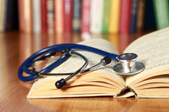 A stethoscope lying on an open book.